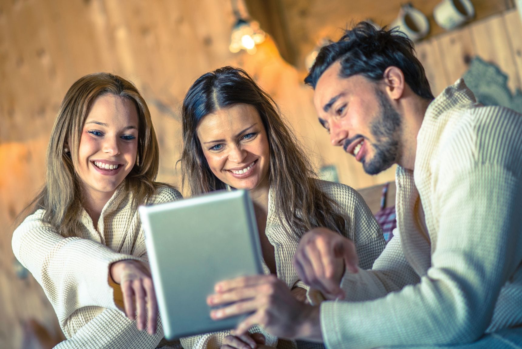 3 people happily looking at an IPad